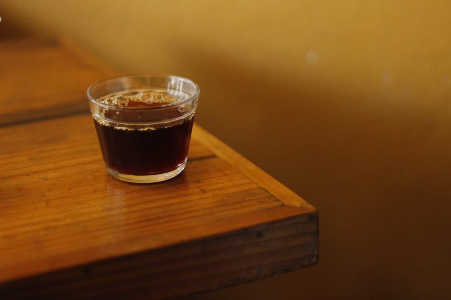 Copo de café coado na quina de uma mesa de madeira